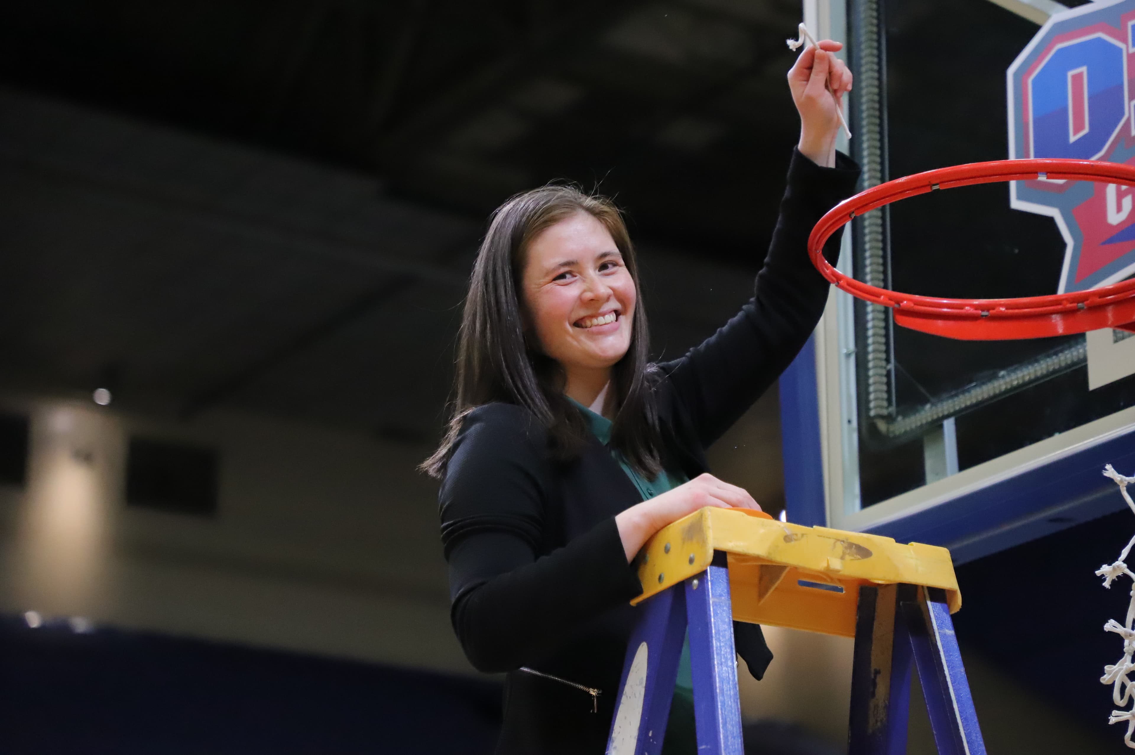 Coach El smiling as she cuts down the net after a conference championship at Shenandoah University.
